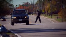 A pedestrian crosses a road in Southern Dallas where there is no crosswalk.