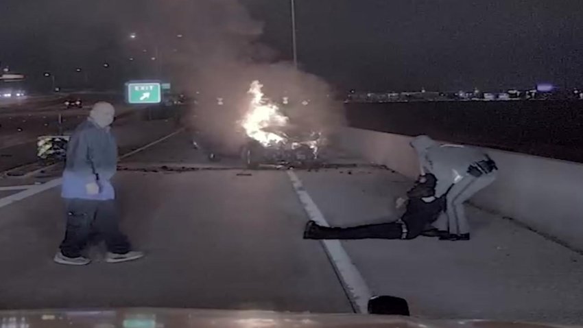 A Texas state trooper rescues a driver from a burning car along the Dallas North Tollway on Jan. 9, 2025.