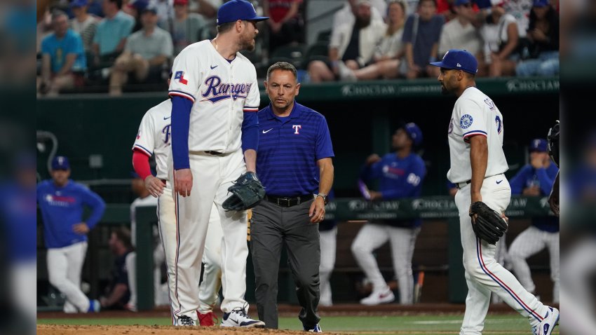 May 12, 2025; Arlington, Texas, USA; Texas Rangers pitcher Luke Jackson (77) is checked on by a trainer after being hit with a batted ball during the ninth inning against the Colorado Rockies at Globe Life Field. Jackson would leave the game after being hit.